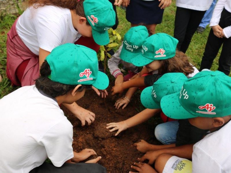 Grupo de crianças com boné Ajibem mexendo na terra